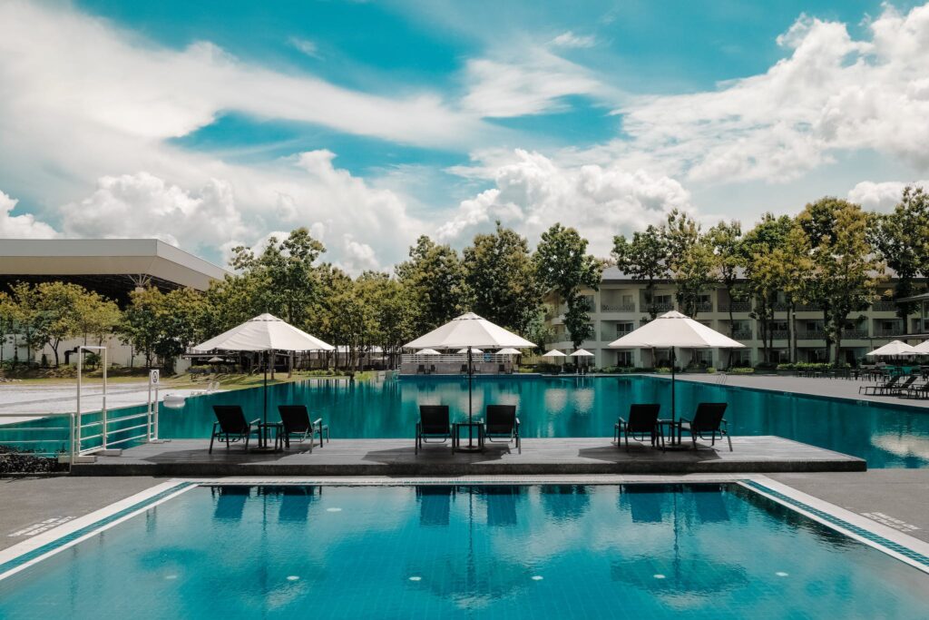 Black Outdoor Lounge Chair in Between Blue Swimming Pool Under White Cloudy Blue Sky